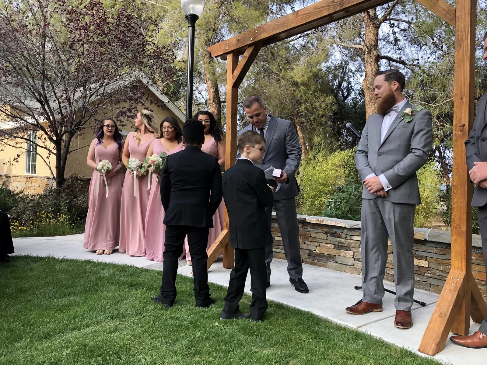 A ceremony at the wooden arbor with bridesmaids in pink