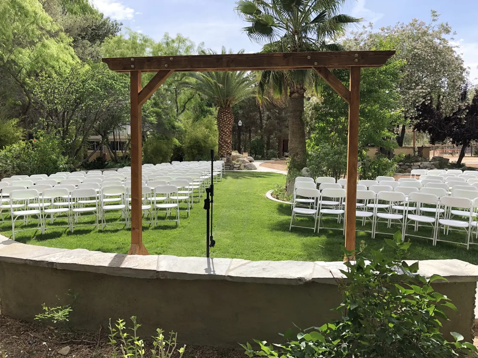 Ceremony lawn at The Garden with a wooden arbor and white chairs