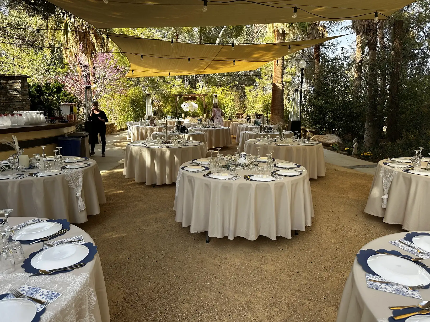 Round tables dressed for an event under the sail shades at The Garden