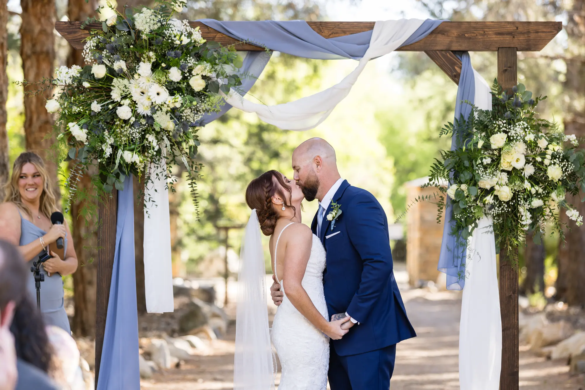 A couple at the flower-draped wooden arch at The Garden in golden-hour light
